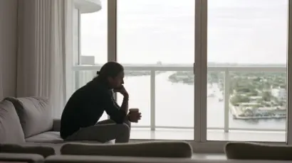 A contemplative man sitting alone in a Fort Lauderdale high-rise condo with morning light off the Intracoastal