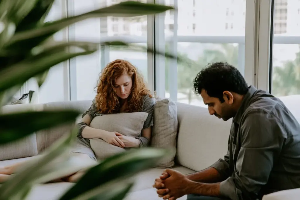 A couple sitting apart on a sofa in a Las Olas apartment, softened posture after tension
