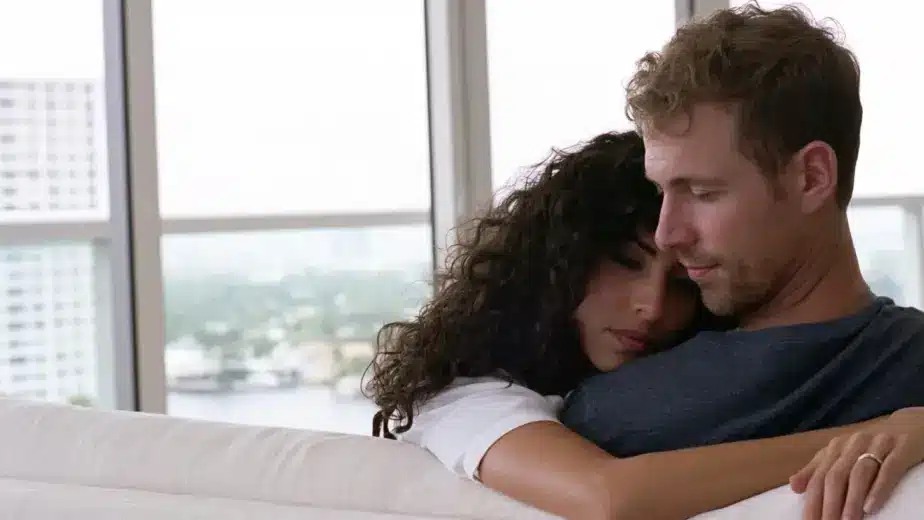 Married couple sitting close on a sofa in a light-filled Las Olas condo in Fort Lauderdale, talking quietly