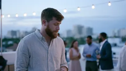 A man standing slightly apart at a rooftop gathering in Las Olas, Fort Lauderdale at dusk