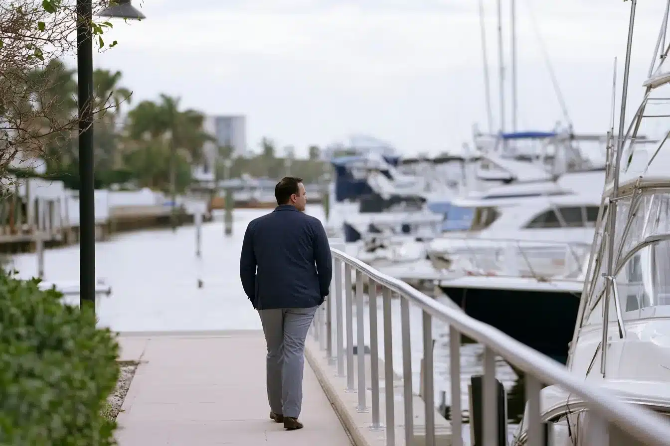 A man walking alone along a Fort Lauderdale waterfront path on an overcast morning