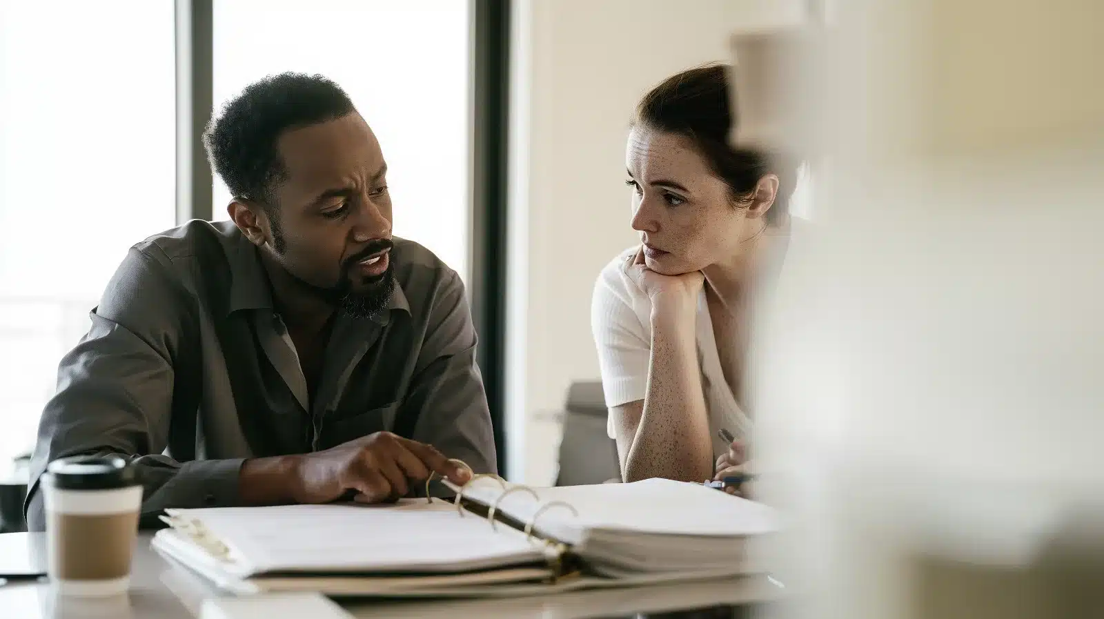 Married couple at a kitchen island with a meticulous household binder between them, showing how control can replace connection in an OCPD relationship