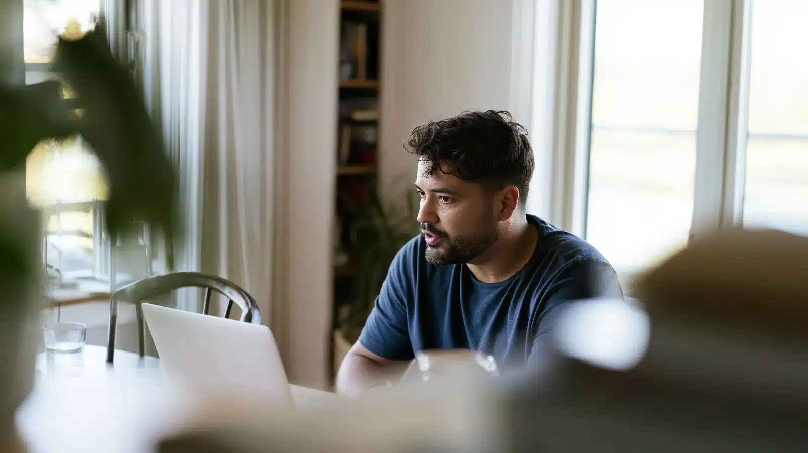 Man in an online therapy session speaking to an empty chair beside his desk, a chairwork exercise for the anxious part beneath perfectionism and control