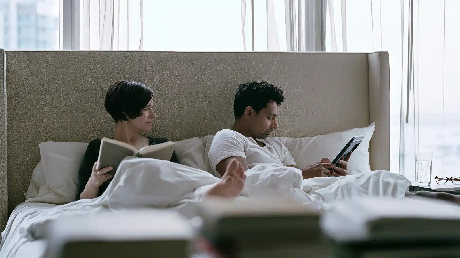 Couple in bed reading, physically close but emotionally distant, illustrating how overcontrol and withdrawal reinforce each other in an OCPD relationship