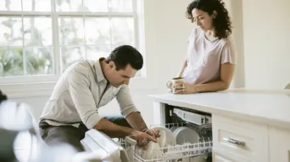 Couple in a South Florida kitchen where one partner carefully reorganizes the dishwasher while the other watches, a common moment in an OCPD relationship