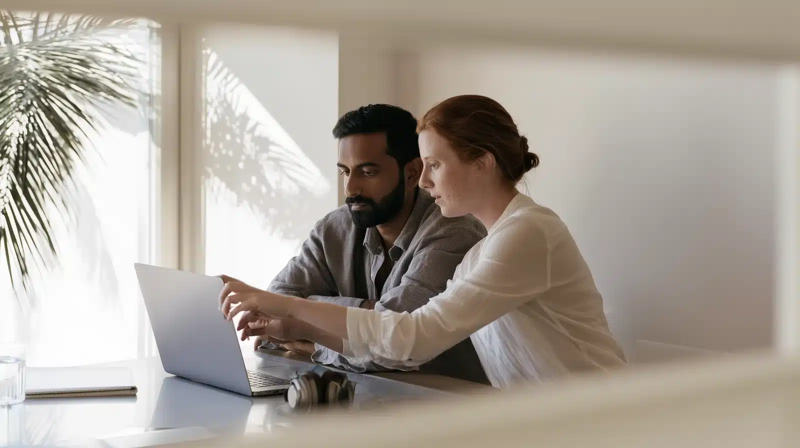 Couple joining an online neurodiverse couples therapy session from their Fort Lauderdale home, headphones on the desk