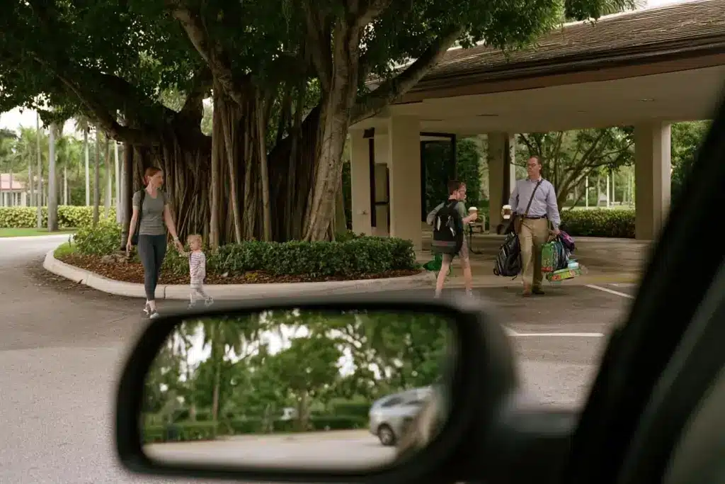 Parents arriving with children at a private school entrance in Fort Lauderdale on an overcast morning
