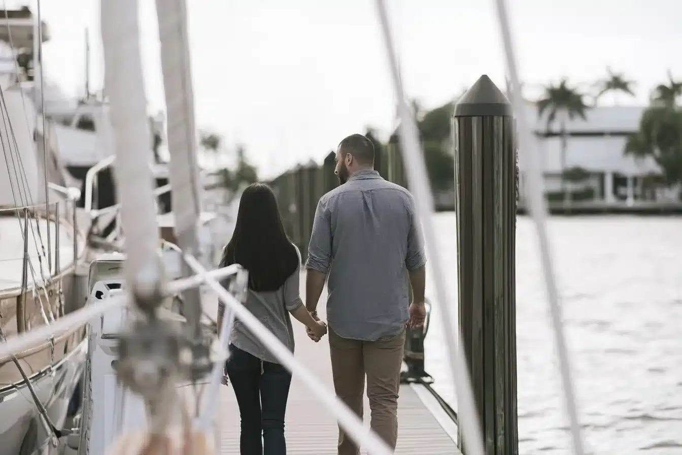 Couple walking hand in hand along a quiet marina walkway in Fort Lauderdale on an overcast morning