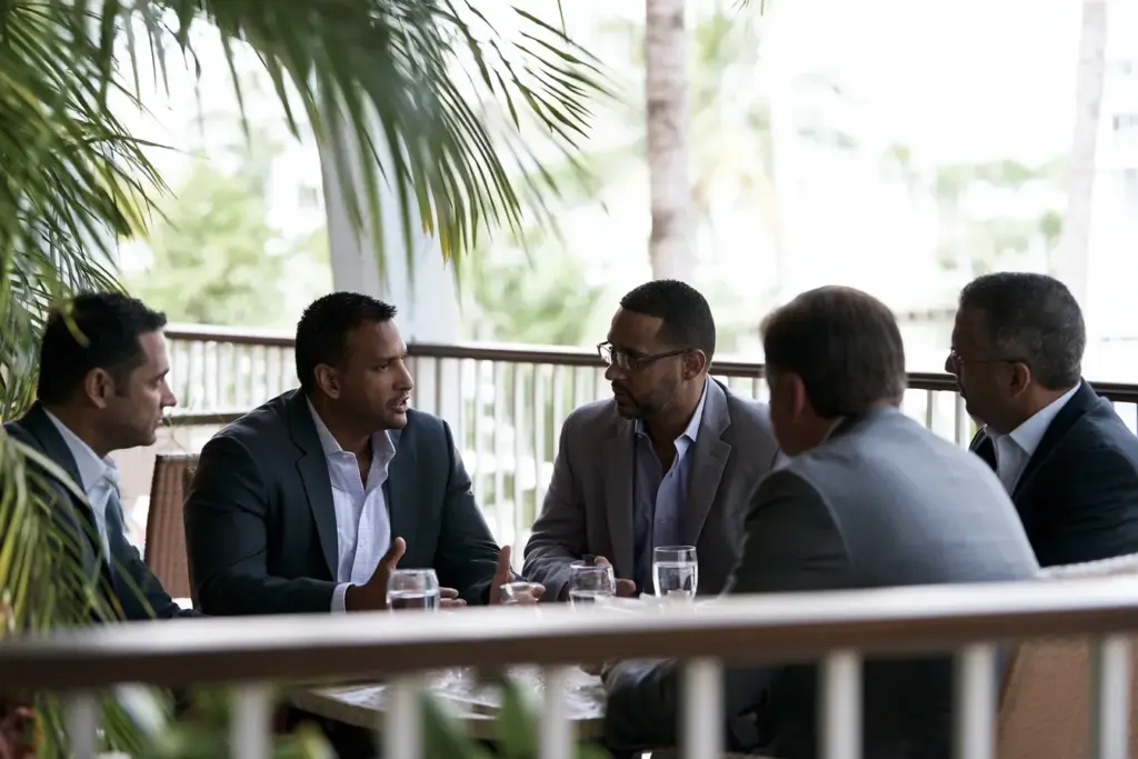 A small group of professional men in conversation on a shaded terrace in Fort Lauderdale