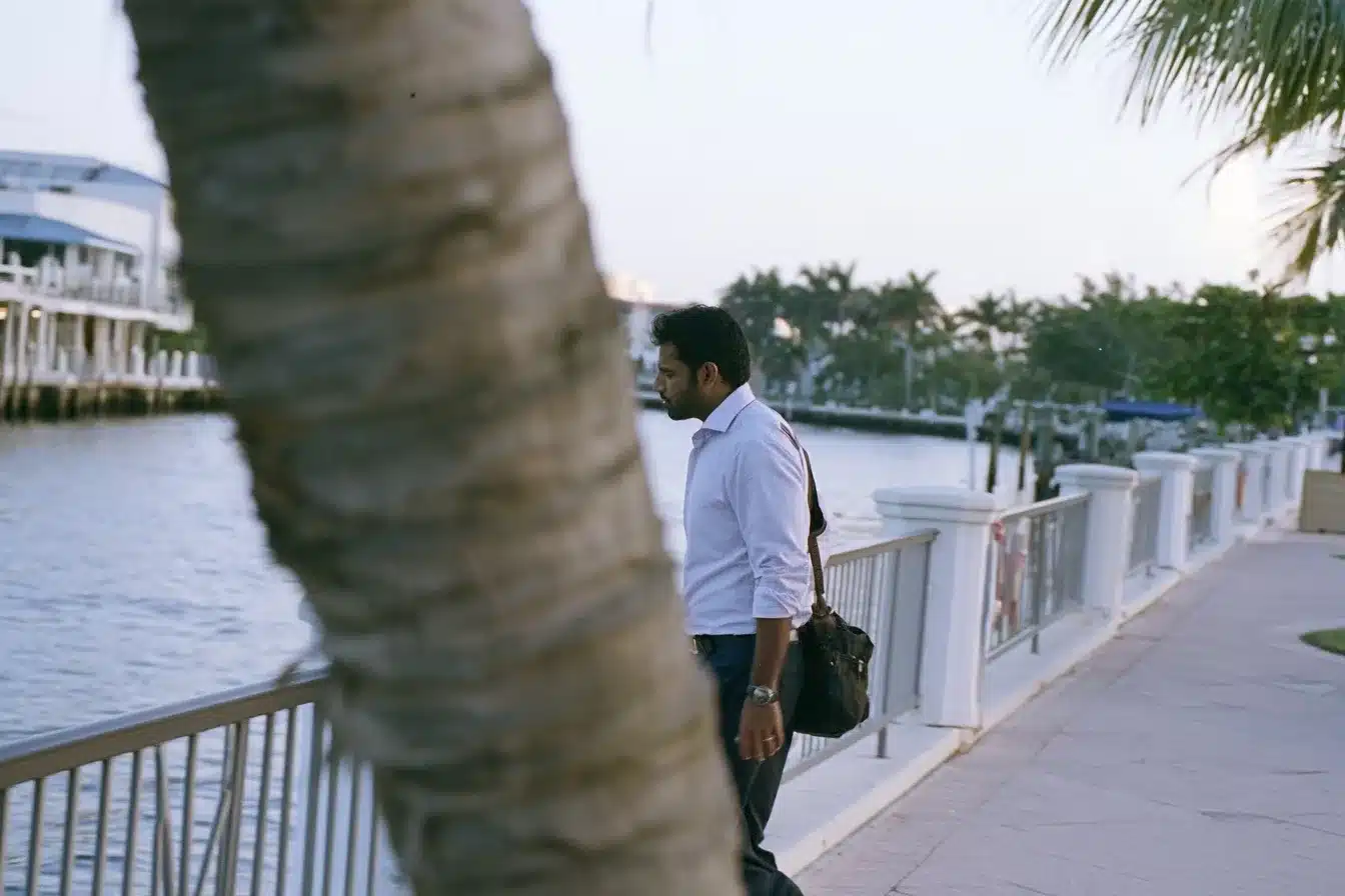 A South Asian professional man walking home along an Intracoastal promenade on a summer evening
