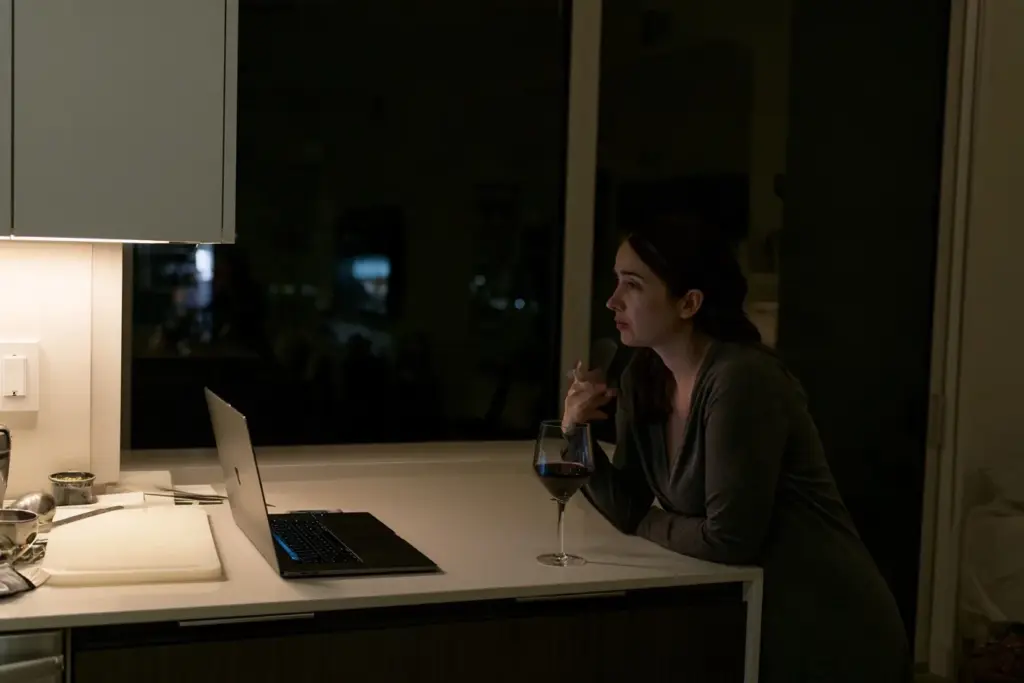 A woman standing alone in a modern South Florida kitchen in the evening, reflecting on work and life